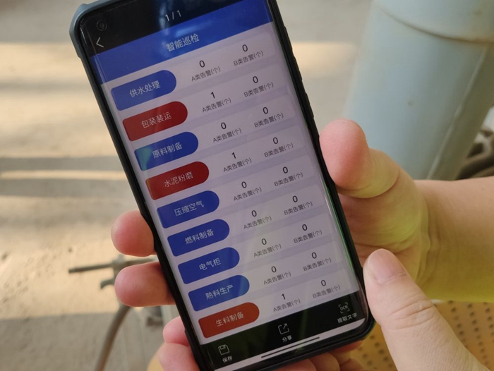 在华新水泥（黄石）有限公司生料车间，现场工作人员正在用手机查看智能巡检app。 新华社记者 万芃琦 摄